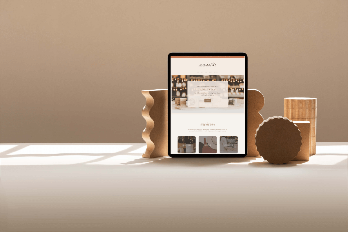 A tablet propped on stylish wooden stands displaying Out in the Sticks Design Co. website by Desert Rose Design, a web designer in Las Vegas